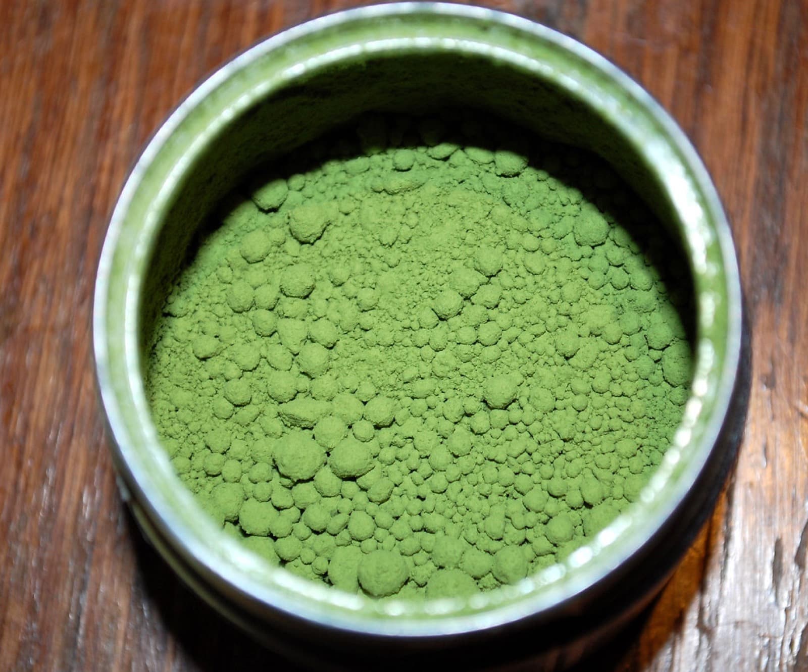 An open tin of vibrant green matcha powder