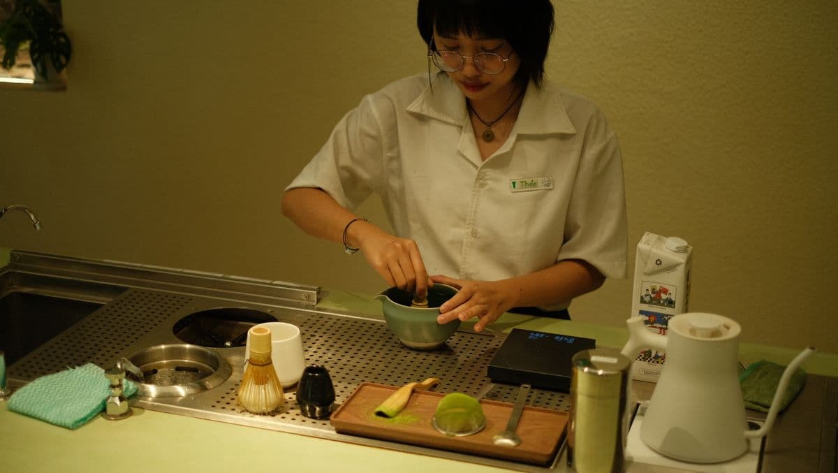 A barista preparing a matcha drink in a modern teahouse