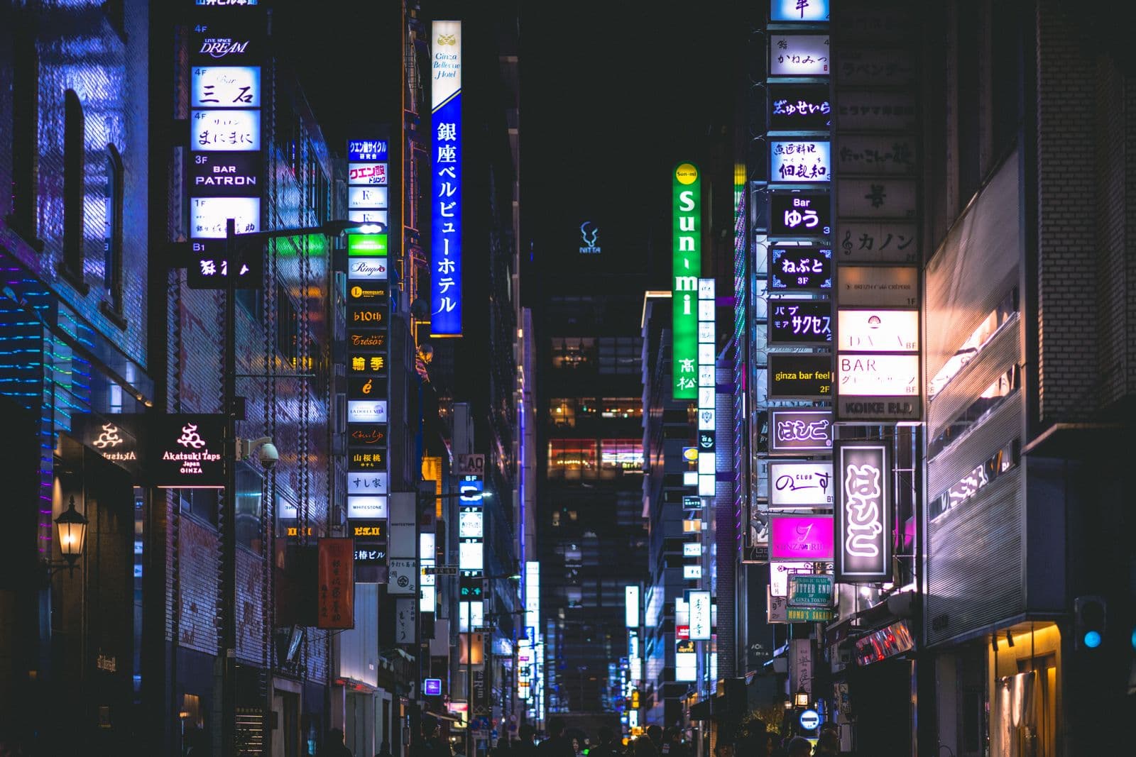A vibrant Ginza street at night in Tokyo, lit by neon signs and storefronts