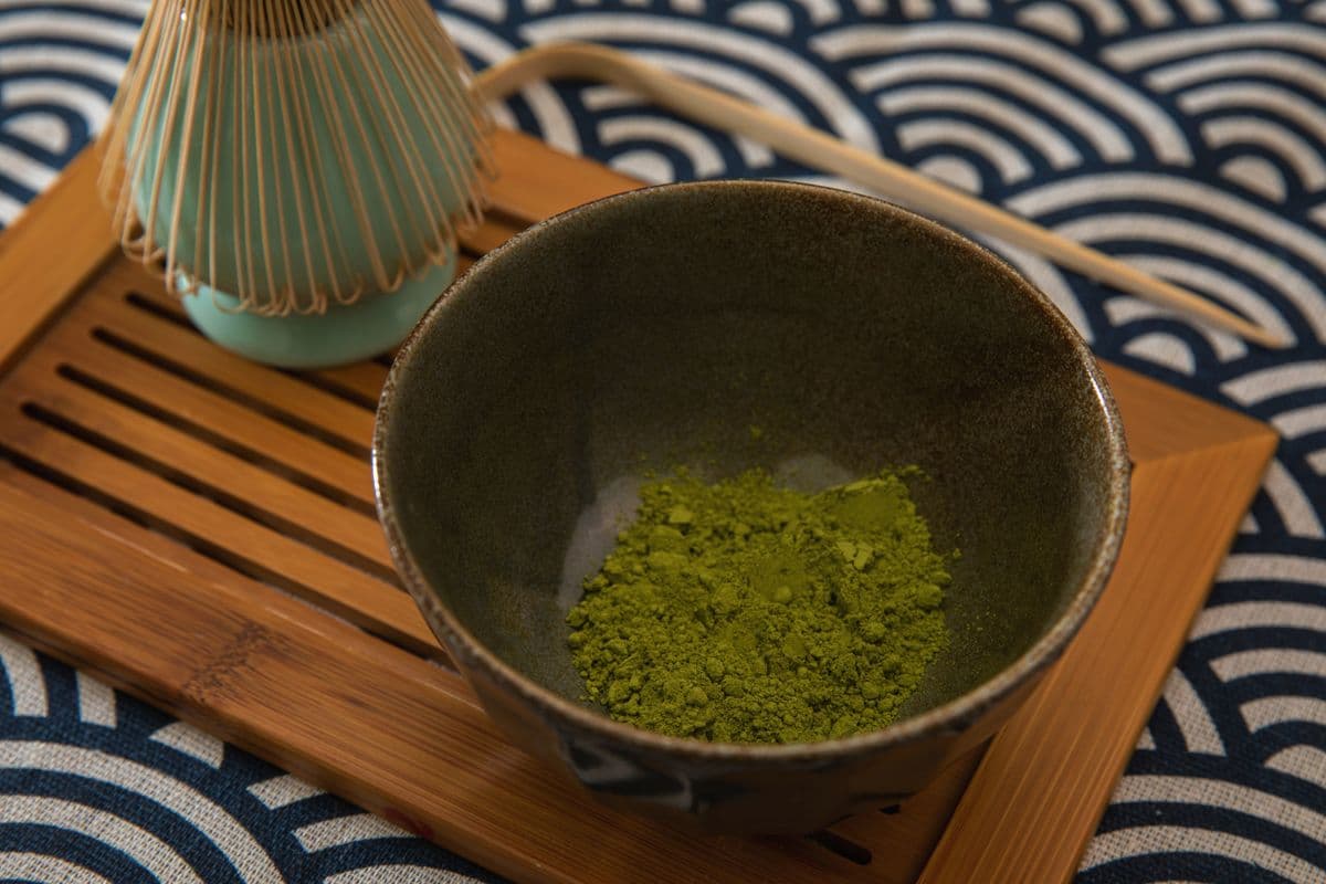 A matcha bowl, bamboo whisk and scoop arranged on a tray for tea preparation