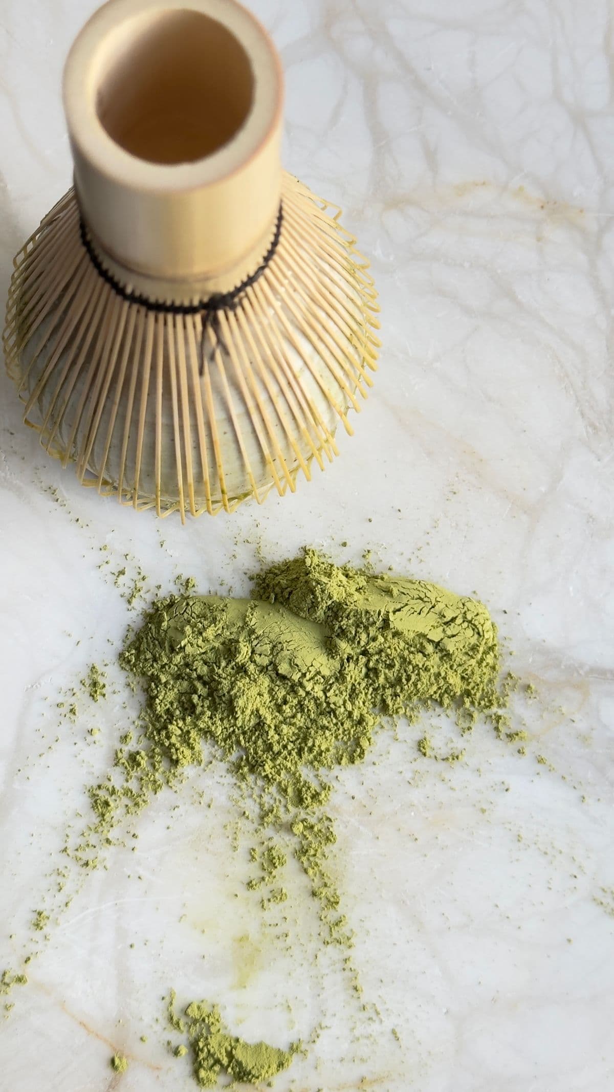 Matcha powder and preparation tools arranged on a marble surface