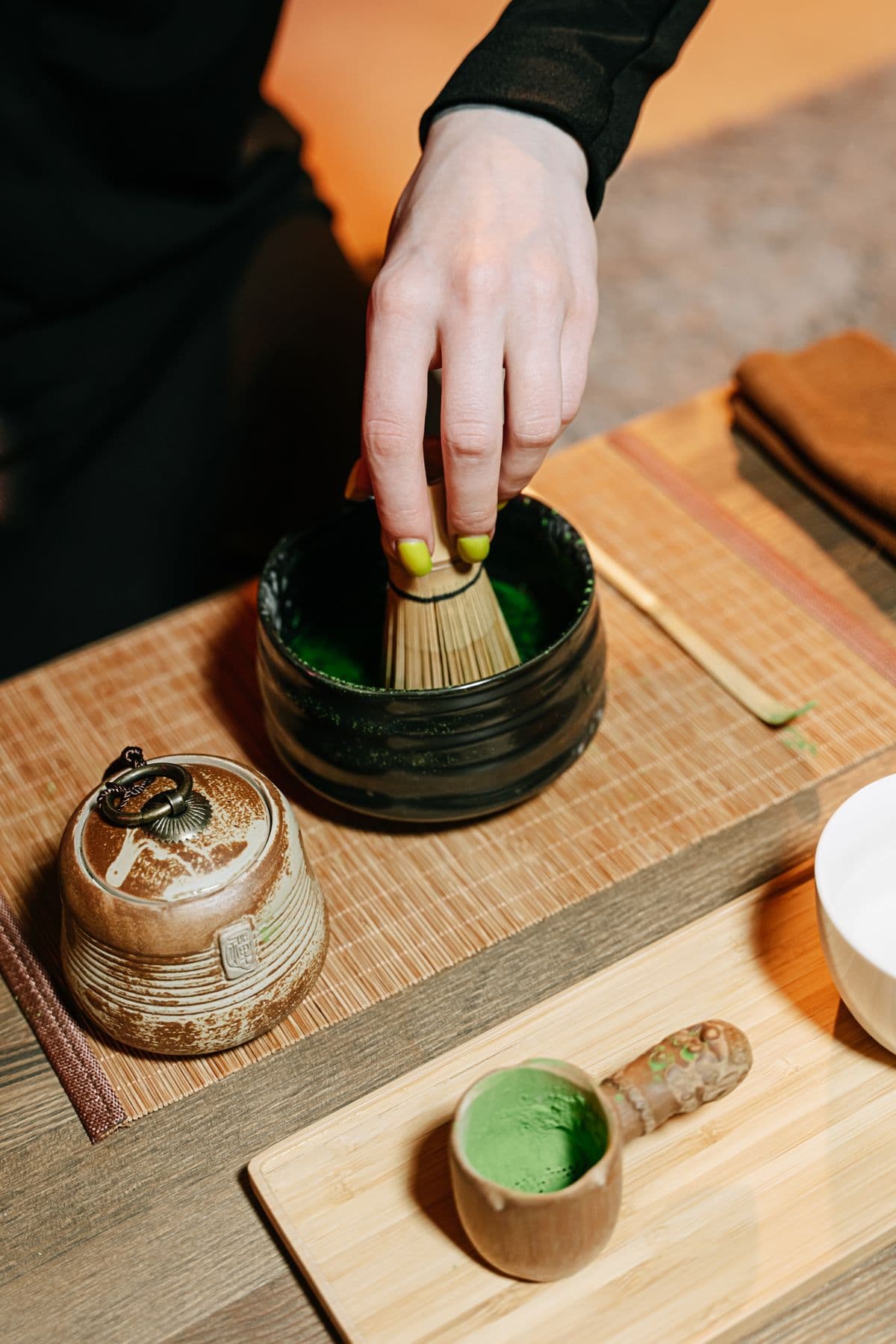 Matcha being whisked into a froth in a ceramic bowl with a bamboo whisk